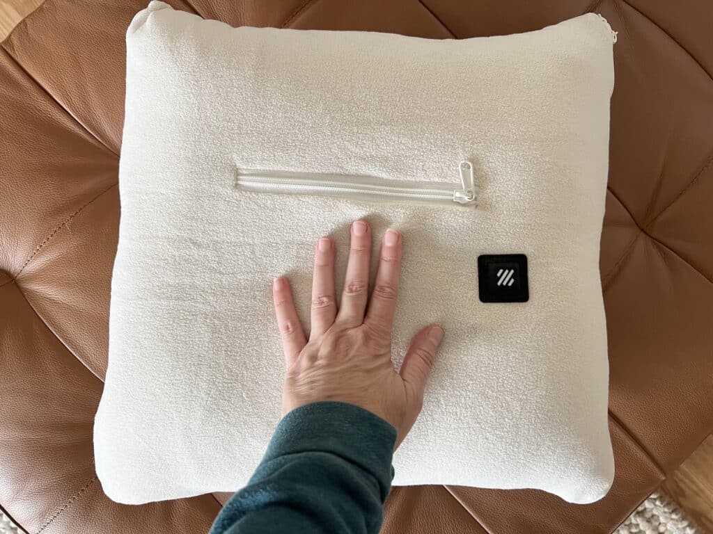 A person's hand holding a Zonli pillow with a zipper on it.