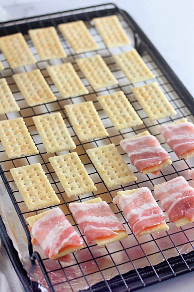 Crackers on a wire rack; some wrapped in bacon.